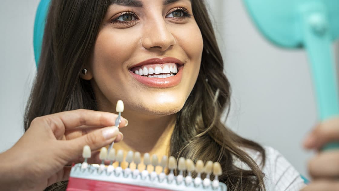 Woman in dental chair with tooth shade guide